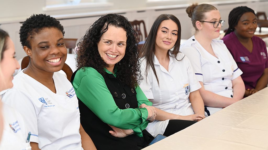 Group of nurses male and female standing outside in a line directly facing the camera and smiling